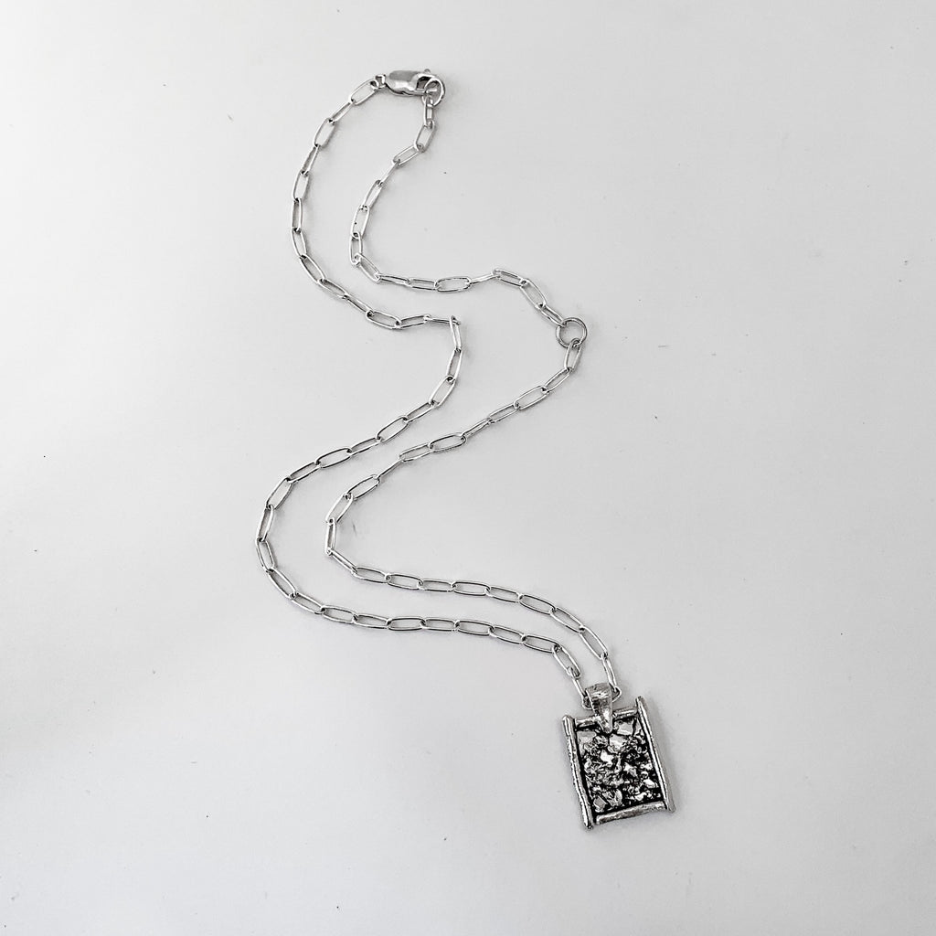 Silver crystal-inspired texture necklace on a white background. Silver chain with large links and rectangular layering pendant. 